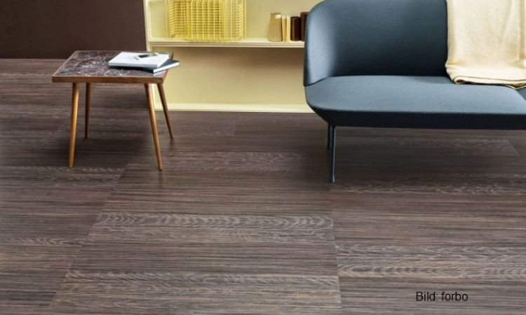 graues Sofa vor braunem Linoleum Boden mit Struktur