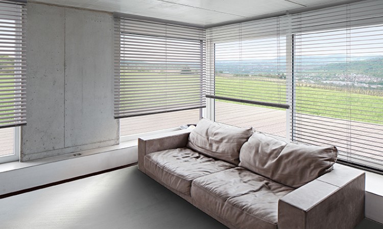 Vertikal-Jalousien im Wohnzimmer mit Betonoptik und Ledersofa